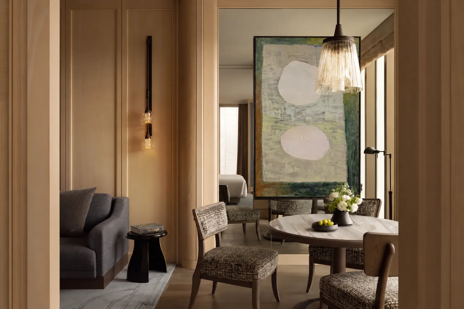 A softly lit room with a large textured artwork beside a lounge chair